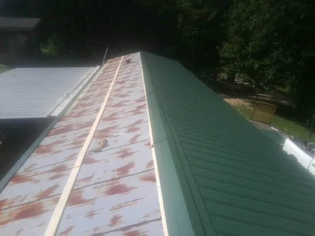 Old rusted panels beside newly installed green metal roofing — Wind Damage Roof Repair by Roofing Brothers in Snowville