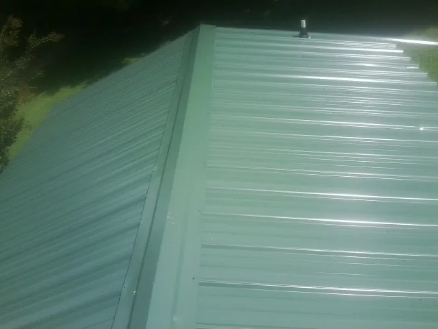 New green metal panels meeting at the ridge of a roof — Flat Roof Repair work by our crew in Snowville