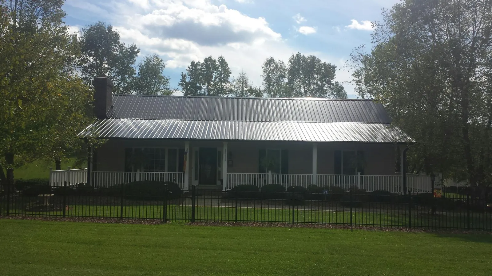 Gray metal roof on a brick ranch with a full width front porch — Gutter Guard Installation work by our crew in Snowville