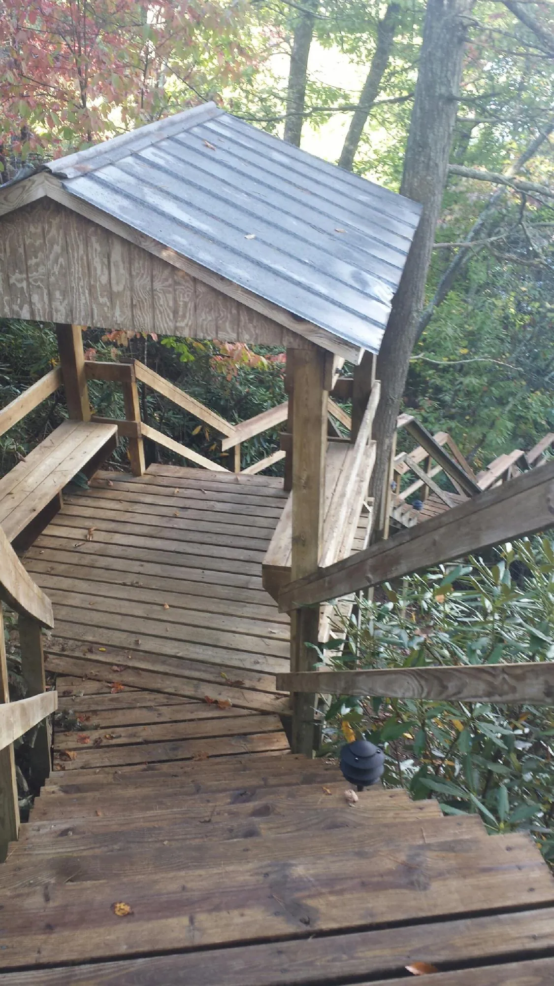 Metal roofed shelter over wooden steps on a wooded walkway — Skylight Repair & Installation work by our crew in Snowville