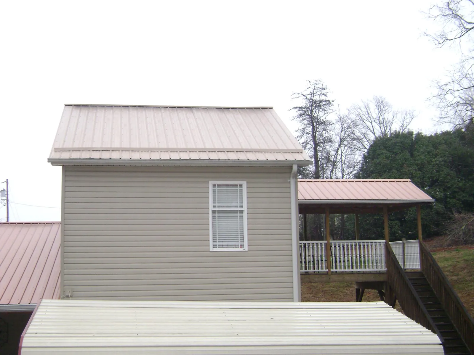 Tan metal roofs on a two story addition and attached porch, from a Roof Replacement job in Snowville