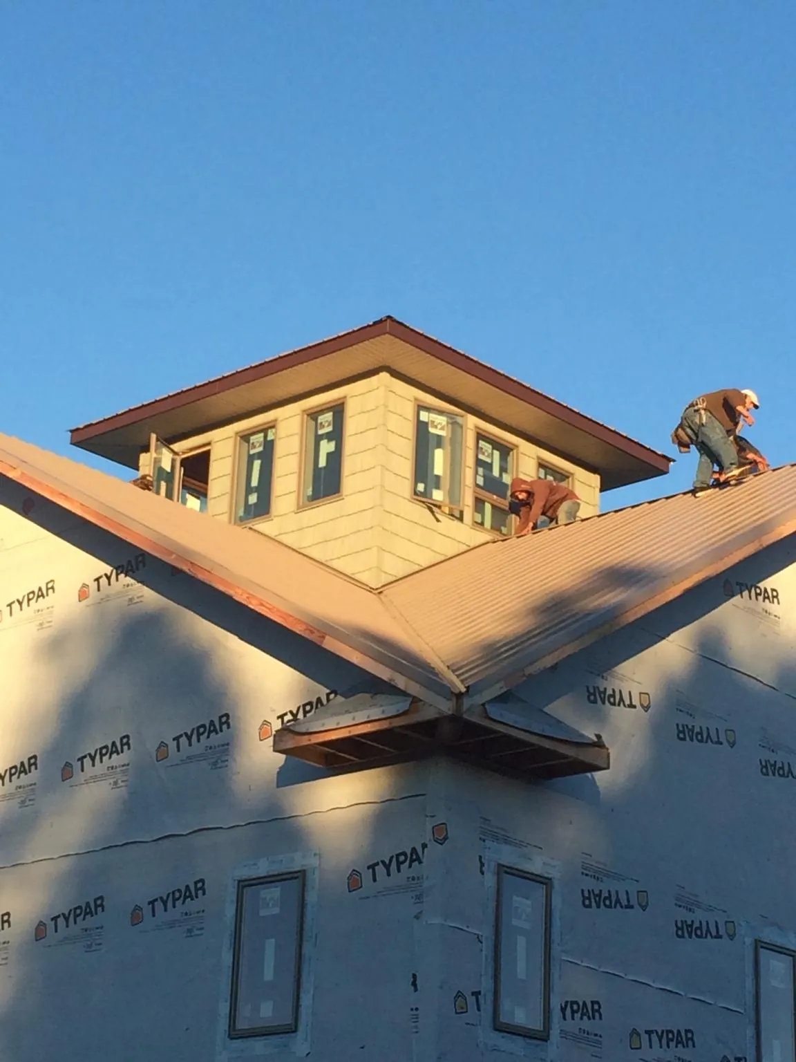 Roofers working around a rooftop cupola on a new metal roof at sunset — Roof Waterproofing in Snowville by Roofing Brothers